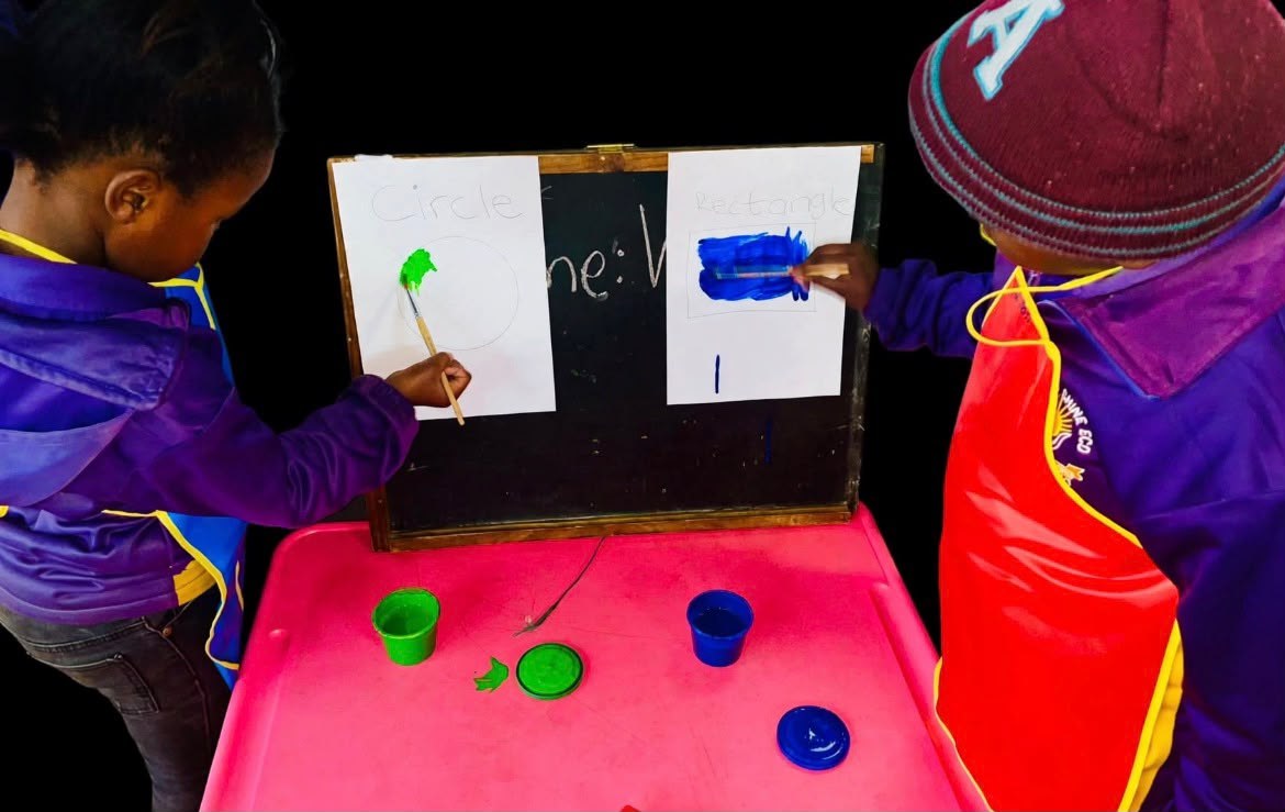 Children painting shapes on an easel
